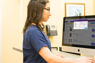 A woman checks the practice’s schedule for the day on her computer.