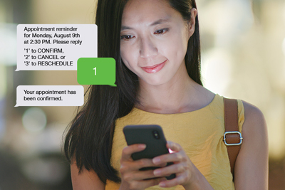 A woman receives messages from her doctor’s office, on her mobile phone.